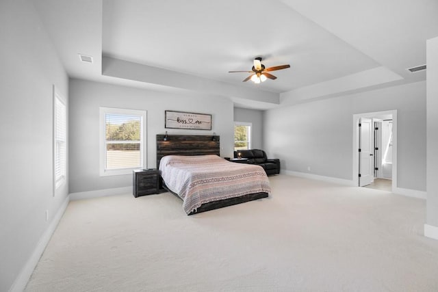 bedroom featuring a raised ceiling, ceiling fan, and light colored carpet