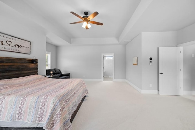 carpeted bedroom with connected bathroom, a tray ceiling, and ceiling fan