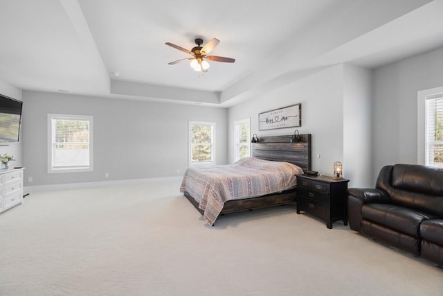 bedroom featuring a raised ceiling, ceiling fan, and light colored carpet