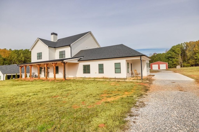 view of front of property featuring covered porch, a garage, an outdoor structure, and a front lawn