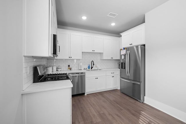 kitchen featuring decorative backsplash, appliances with stainless steel finishes, sink, white cabinets, and hardwood / wood-style floors