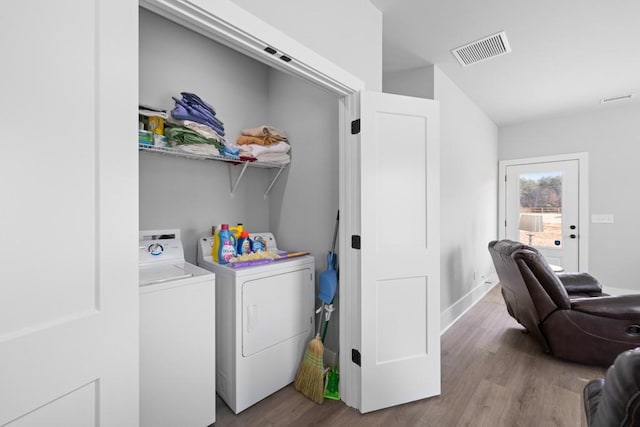 laundry area with light hardwood / wood-style floors and washing machine and dryer