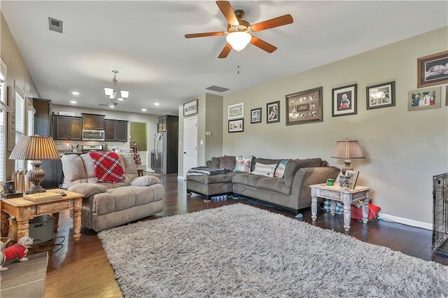 living room with ceiling fan with notable chandelier and dark hardwood / wood-style floors