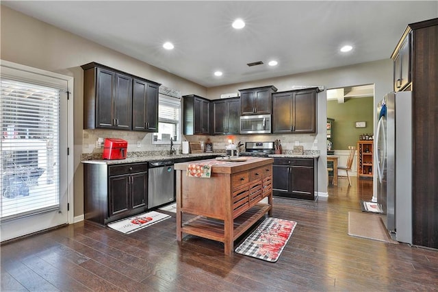 kitchen with dark brown cabinetry, stainless steel appliances, and dark hardwood / wood-style floors