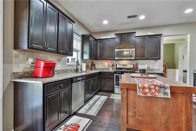 kitchen with backsplash, dark wood-type flooring, sink, appliances with stainless steel finishes, and a kitchen island