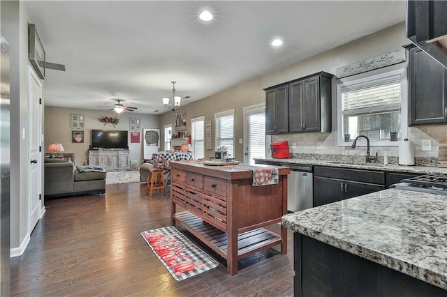 kitchen featuring sink, tasteful backsplash, light stone counters, dark hardwood / wood-style flooring, and ceiling fan with notable chandelier