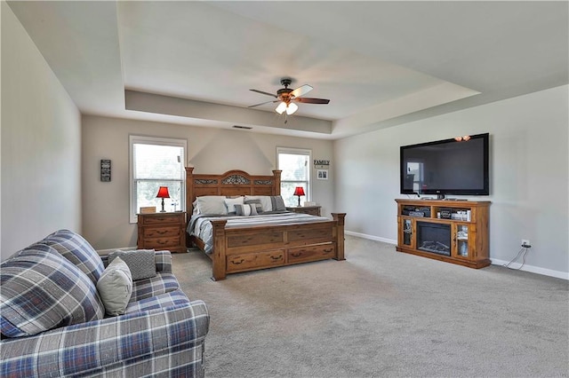 bedroom with ceiling fan, multiple windows, and a tray ceiling