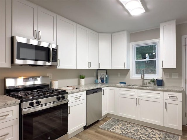 2068 Verbena St NW, Atlanta, GA 30314 - kitchen with appliances with stainless steel finishes, light wood-style floors, white cabinets, and crown molding