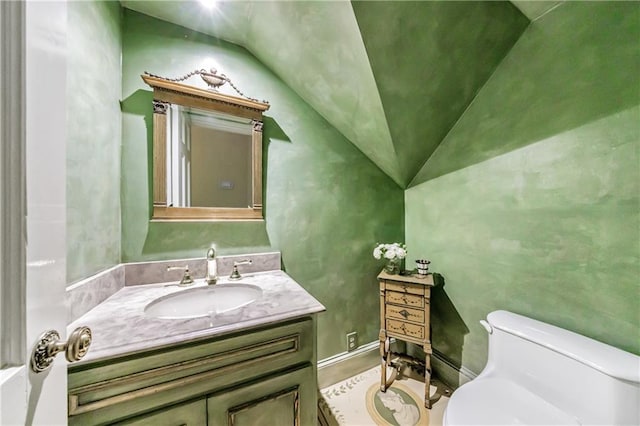 bathroom with lofted ceiling, toilet, and vanity