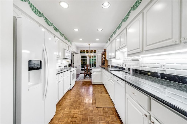 kitchen with sink, white appliances, light parquet floors, white cabinets, and a chandelier