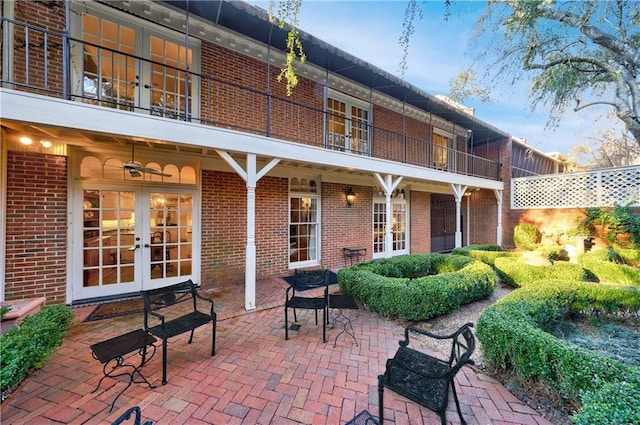 rear view of property featuring french doors, a balcony, and a patio