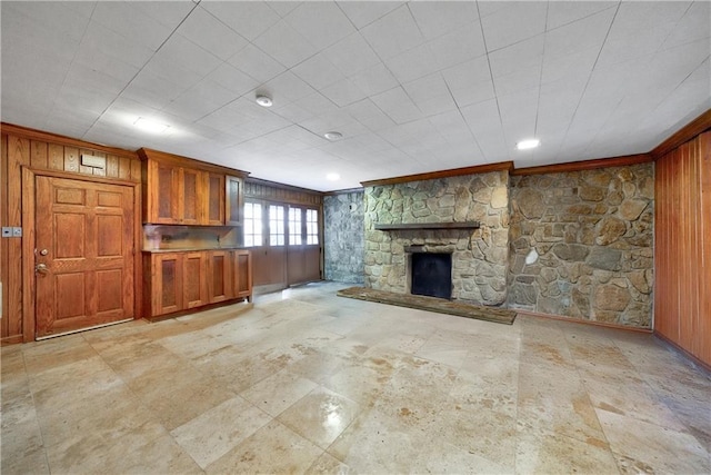 unfurnished living room featuring wooden walls and a stone fireplace