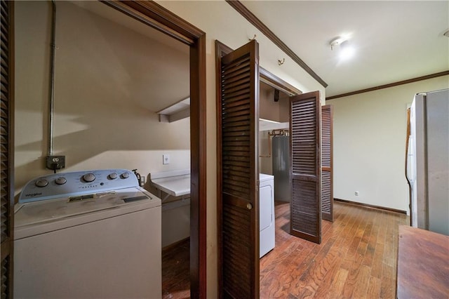 laundry area with ornamental molding, washer / dryer, and light hardwood / wood-style floors