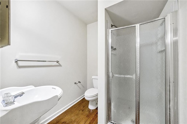 bathroom featuring vaulted ceiling, wood-type flooring, sink, toilet, and a shower with door