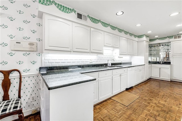 kitchen with sink, white dishwasher, white cabinets, kitchen peninsula, and light parquet flooring