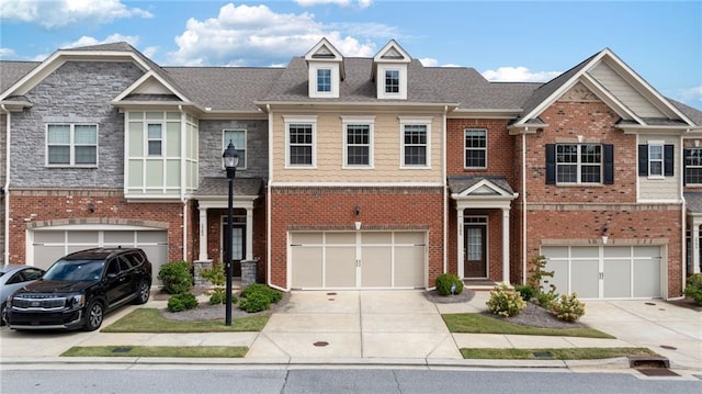 townhome / multi-family property with driveway and brick siding