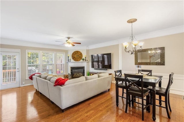 living room featuring hardwood / wood-style floors, crown molding, and ceiling fan with notable chandelier