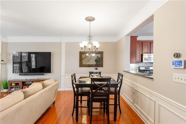 dining room with hardwood / wood-style floors, a notable chandelier, and ornamental molding