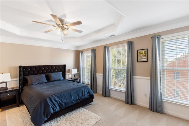 carpeted bedroom featuring multiple windows, crown molding, ceiling fan, and a tray ceiling