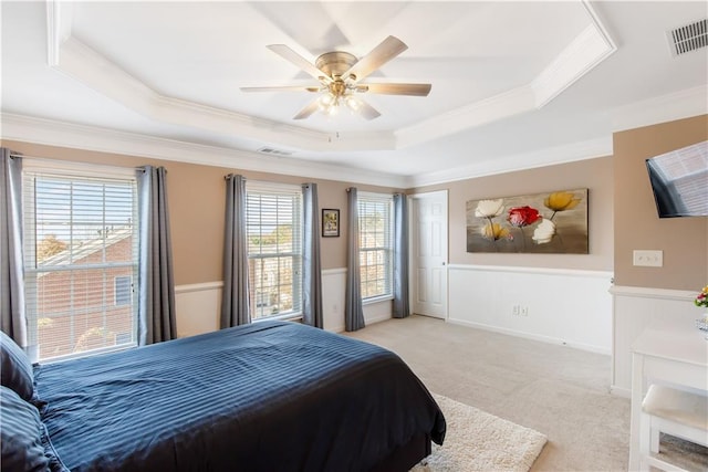 bedroom with ceiling fan, ornamental molding, a raised ceiling, and light colored carpet