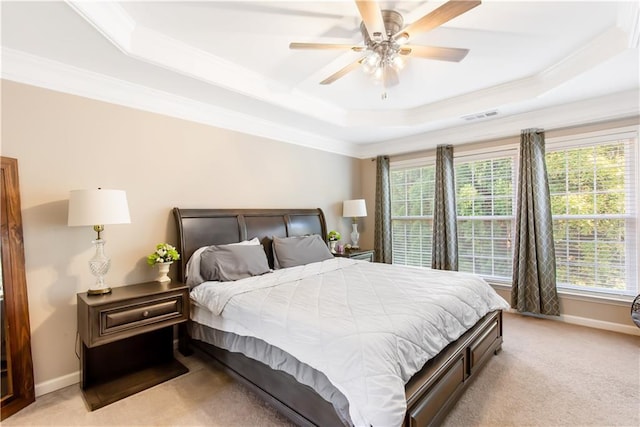 bedroom featuring ceiling fan, ornamental molding, a tray ceiling, and light carpet