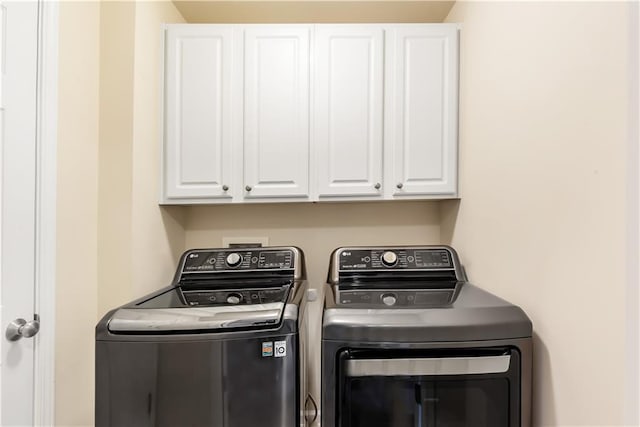 laundry area with separate washer and dryer and cabinets