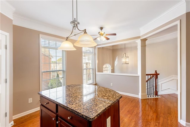 kitchen with crown molding, dark stone countertops, pendant lighting, and light hardwood / wood-style floors