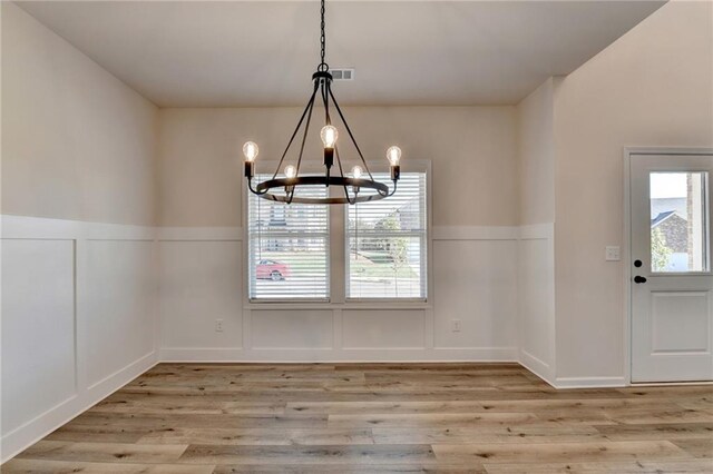 58 Longhorn Way, Auburn, GA 30011 - unfurnished dining area with a decorative wall, a notable chandelier, light wood-style flooring, and a wainscoted wall