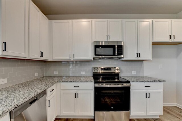 58 Longhorn Way, Auburn, GA 30011 - kitchen with light wood-style flooring, white cabinets, light stone countertops, and stainless steel appliances