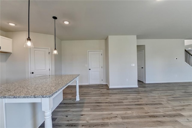 58 Longhorn Way, Auburn, GA 30011 - kitchen featuring decorative light fixtures, light stone countertops, baseboards, light wood-style floors, and white cabinetry
