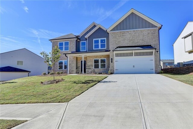 58 Longhorn Way, Auburn, GA 30011 - craftsman-style house with board and batten siding, driveway, a front yard, a garage, and brick siding