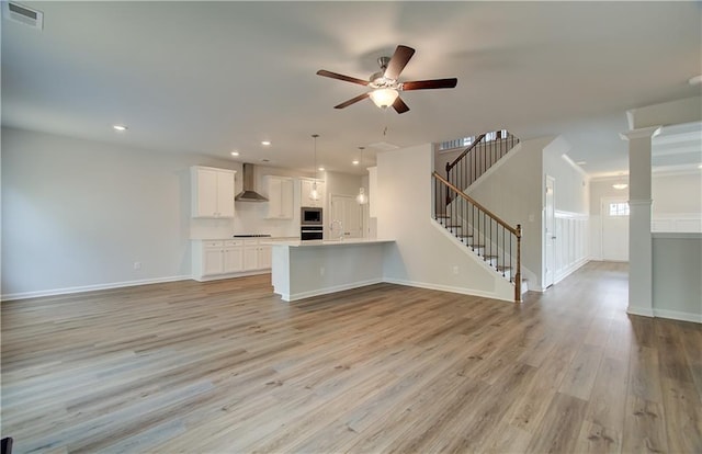 unfurnished living room with ceiling fan, visible vents, stairway, recessed lighting, and light wood finished floors