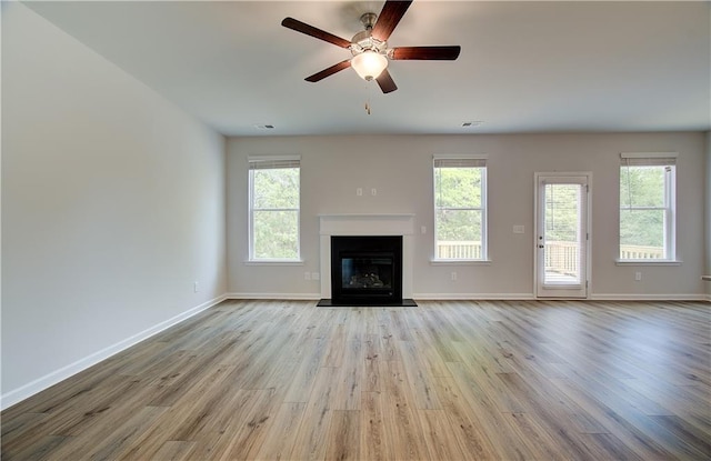 unfurnished living room with visible vents, baseboards, ceiling fan, wood finished floors, and a glass covered fireplace
