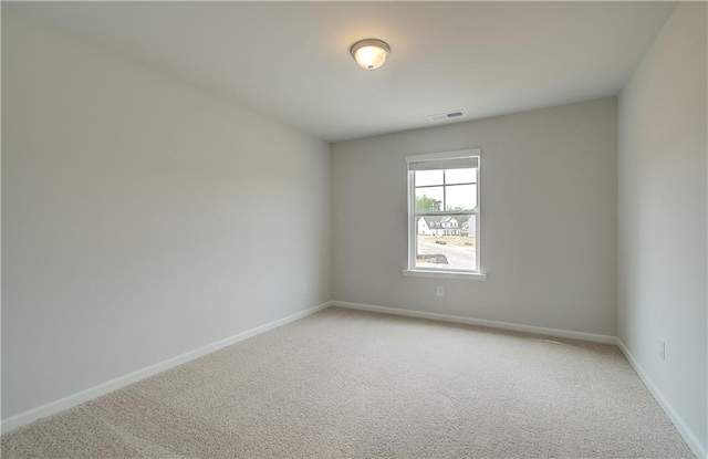 spare room featuring light carpet, visible vents, and baseboards