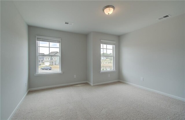 carpeted empty room featuring visible vents and baseboards