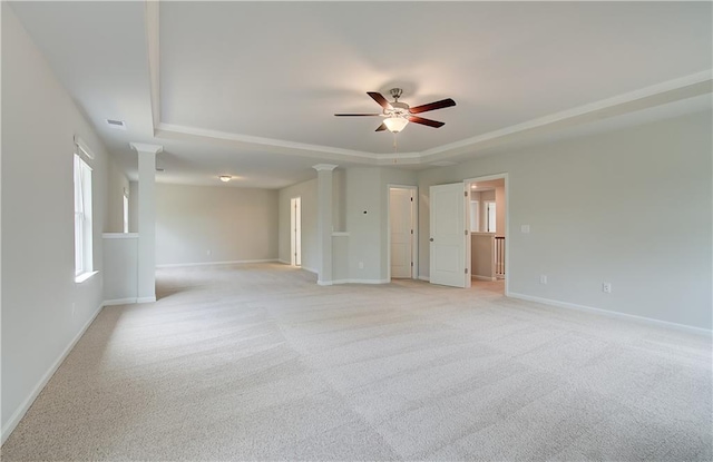 unfurnished room with a tray ceiling, baseboards, and ornate columns
