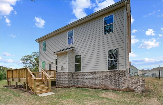 back of property featuring stairs, brick siding, a wooden deck, and a lawn