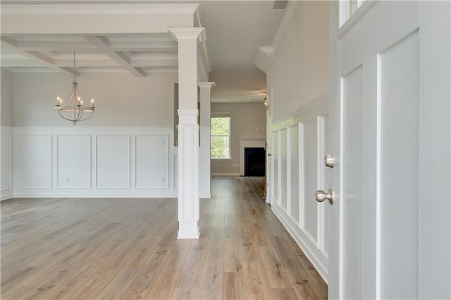 entryway featuring light wood-style flooring, beam ceiling, coffered ceiling, a decorative wall, and ceiling fan with notable chandelier