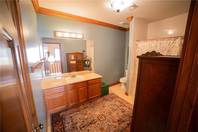 bathroom with tile patterned floors, vanity, toilet, and crown molding