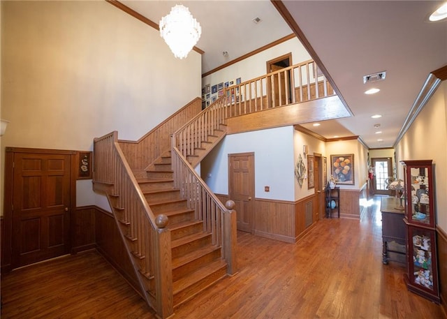 staircase featuring crown molding, hardwood / wood-style flooring, and an inviting chandelier