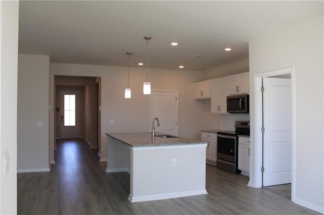 kitchen featuring white cabinetry, sink, hanging light fixtures, stainless steel appliances, and an island with sink