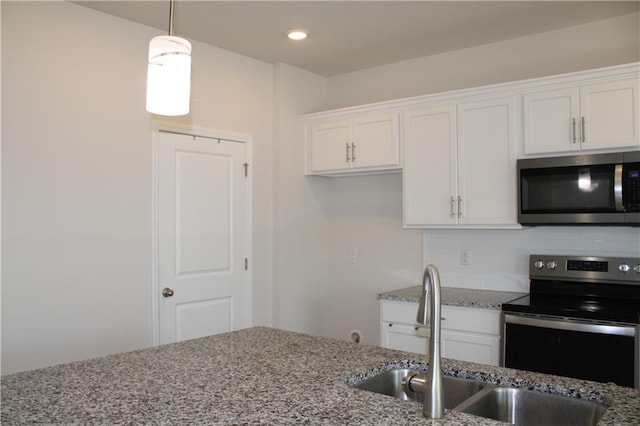 kitchen featuring appliances with stainless steel finishes, light stone counters, sink, white cabinetry, and hanging light fixtures