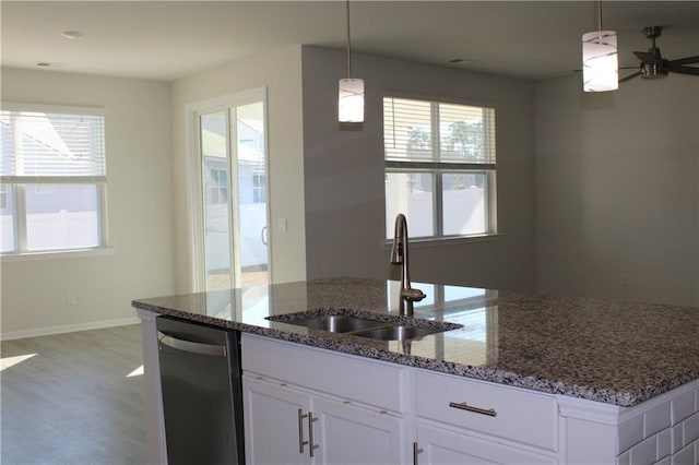 kitchen featuring decorative light fixtures, white cabinetry, sink, and dark stone counters