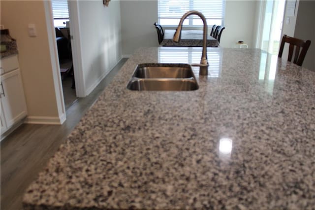 kitchen featuring light stone countertops, white cabinets, dark wood-type flooring, and sink