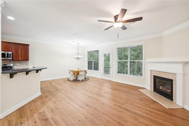 living room featuring crown molding, ceiling fan with notable chandelier, light hardwood / wood-style flooring, and a premium fireplace