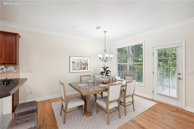 dining room featuring a notable chandelier, light wood-type flooring, and crown molding