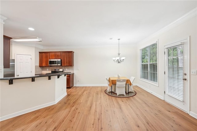 kitchen with light hardwood / wood-style flooring, stainless steel appliances, a kitchen bar, and hanging light fixtures