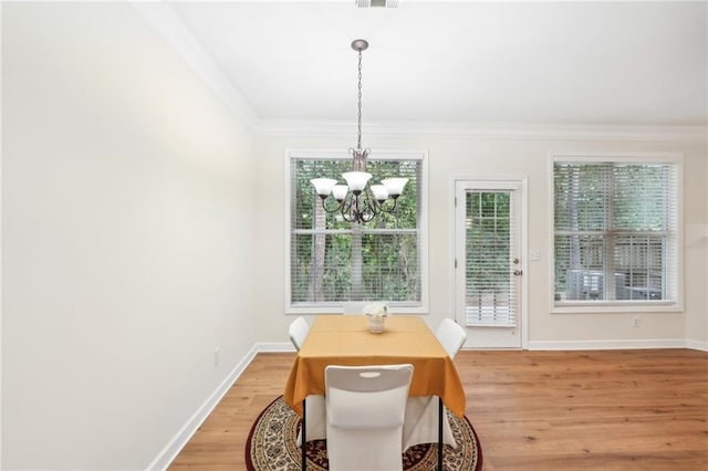 dining room featuring ornamental molding, hardwood / wood-style floors, and a notable chandelier