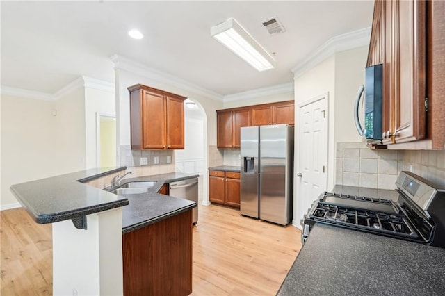 kitchen featuring sink, kitchen peninsula, appliances with stainless steel finishes, light wood-type flooring, and decorative backsplash