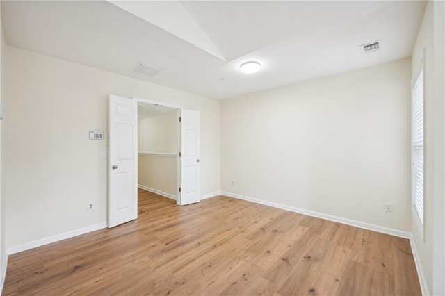 empty room featuring vaulted ceiling and light hardwood / wood-style flooring